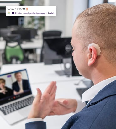 Man with a hearing aid using sign language in a video call, promoting accessibility and inclusion.