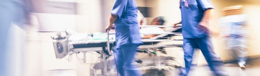 nurses rushing by with patient in gurney